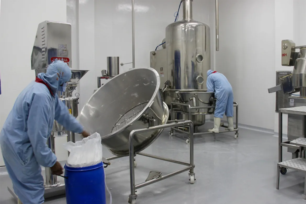 Technicians in protective clothing operating process equipment in a clean factory
